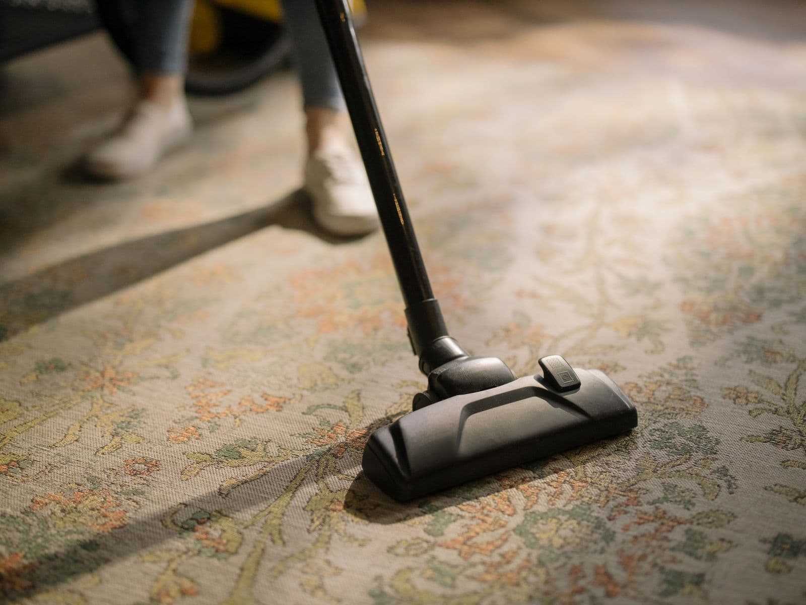 Close-up of carpet cleaning equipment in use on a patterned carpet