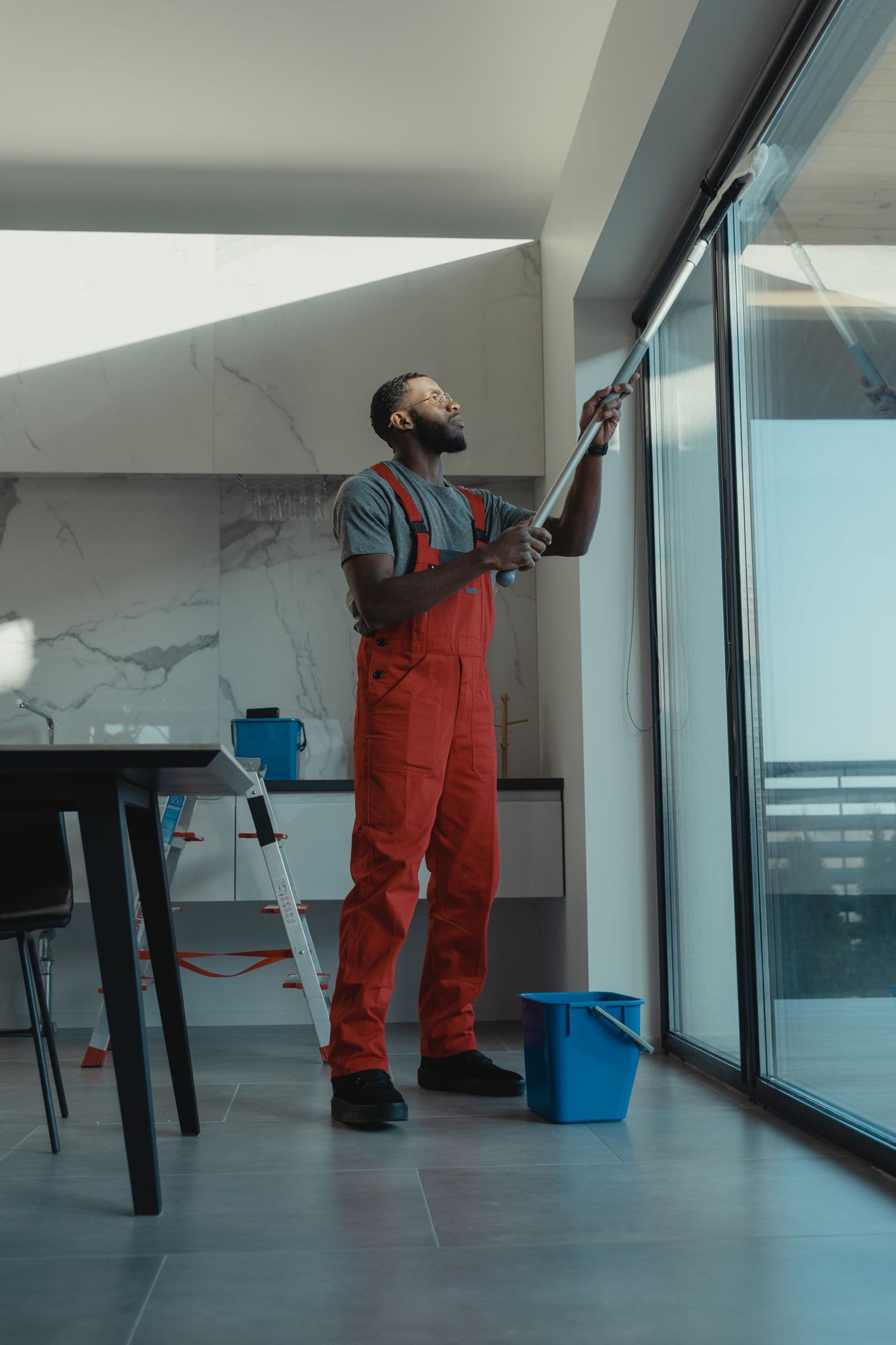 Professional cleaner washing large facility windows in a modern interior